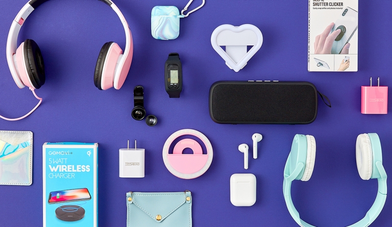 Overhead image of electronics on purple background, including headphones, earbuds, chargers, phone rings and stands