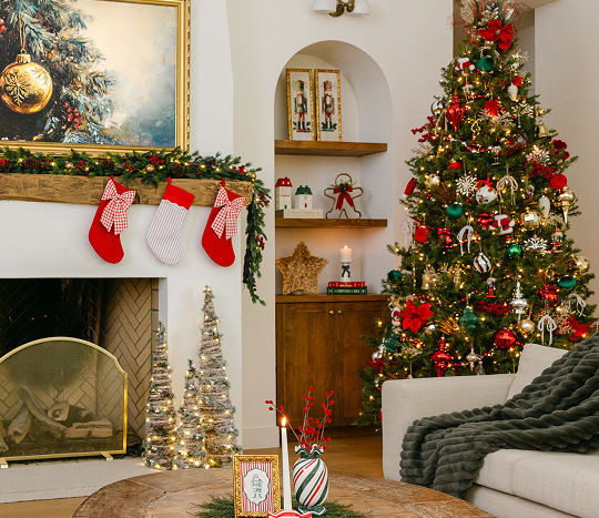 A living room is decorated with classic Christmas decorations from pOpshelf including a festive Christmas tree, a fireplace finished with garland and stockings, and holiday accents sitting on accent tables throughout the room.