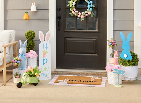 Front porch decorated for spring and easter with egg wreath, bunny mat, bunny porch leaner, eggs, bunnies, carrots & more.