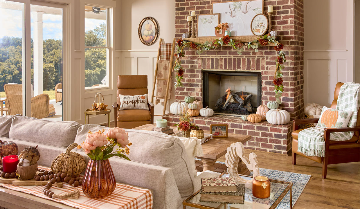 Living room decorated for fall with pumpkin decor, fall pillows and throws, fall candles, fall wall signs, and fall floral.