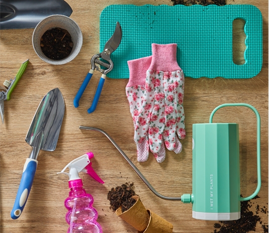 Tabletop with gardening tools, gloves, gardening accessories, and watering can from pOpshelf