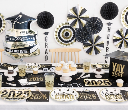 Grad party table featuring black & gold balloons, paper party supplies, foil decorations, and more from pOpshelf.