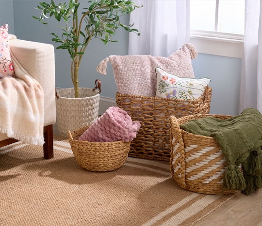 Decorative natural woven baskets filled with stylish pillows and throws.