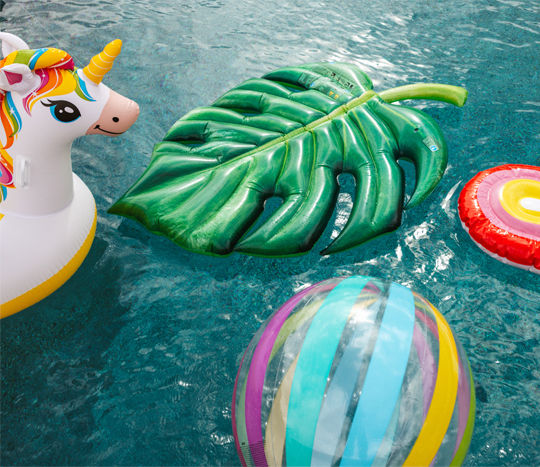 Swimming pool with colorful inflatable floats, ride-ons,  and rafts from pOpshelf.
