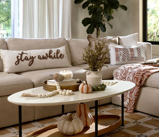 A living room with neutral colored decor features fall accents like affordable pumpkin themed decor from pOpshelf.