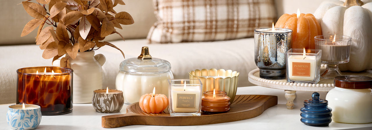 Various fall jar candles and pumpkin-shaped candles in fall scents.
