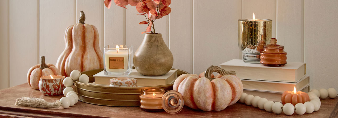 Various fall jar candles and pumpkin-shaped candles in fall scents.