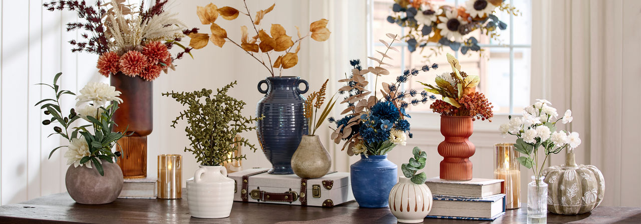Fall floral bushes, fall branches, and floral picks in vases and premade fall floral arrangements on an entryway table.