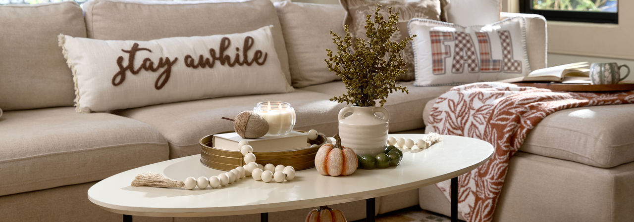 Living room decorated for fall with fall pillows and throws, pumpkin and fall decor, fall candles, and fall floral.