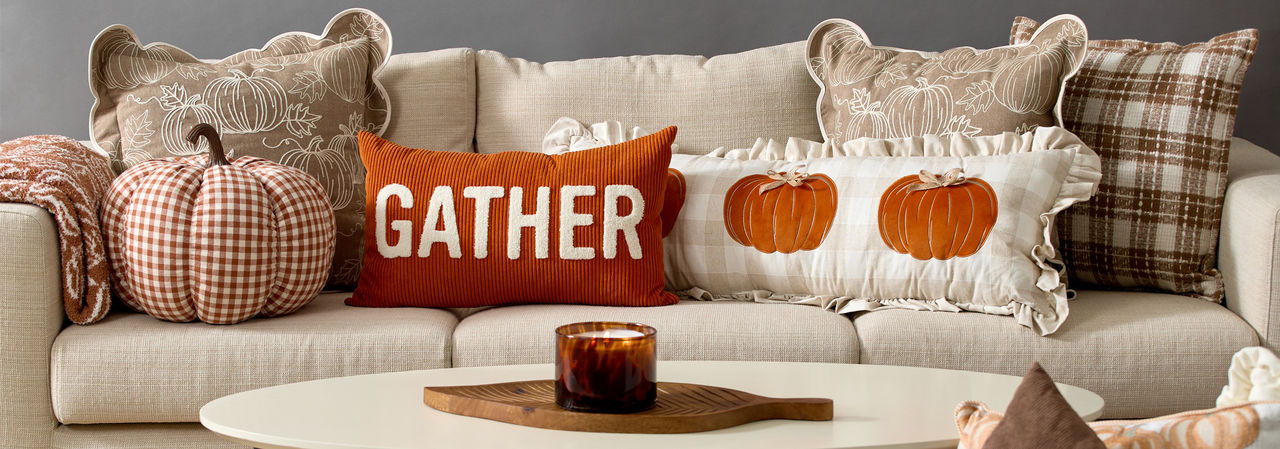 Fall pillows and throws in various colors and designs on a sofa.